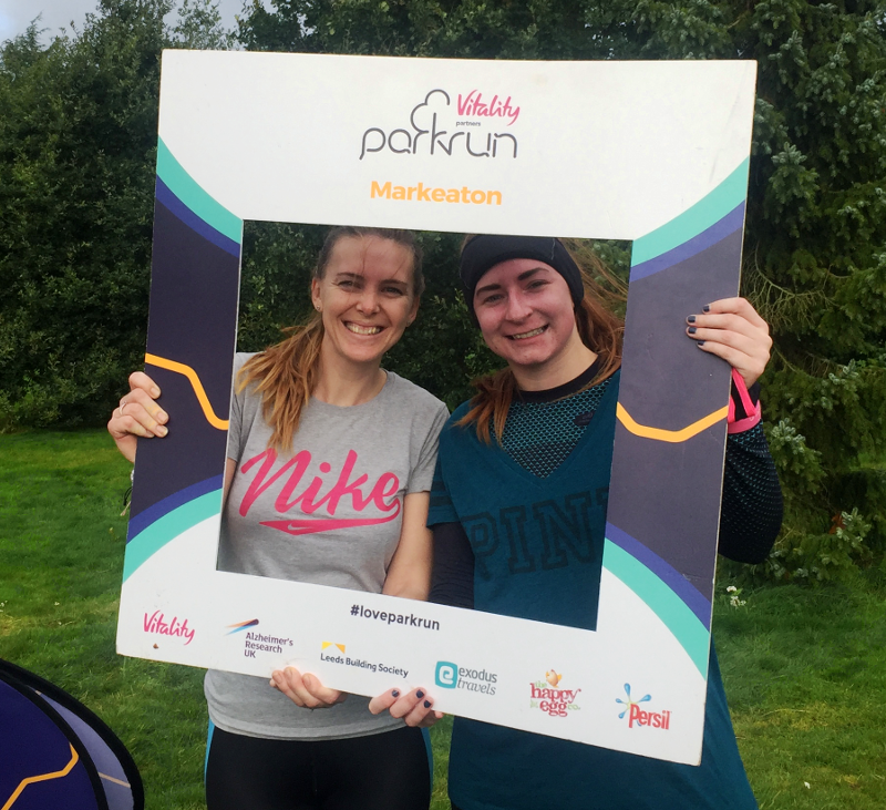 Two members of Contours staff peer through a Parkrun winners window after a successful social run